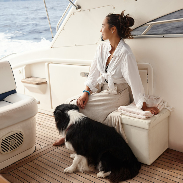 A woman and her dog enjoy the view from the stern of a yacht