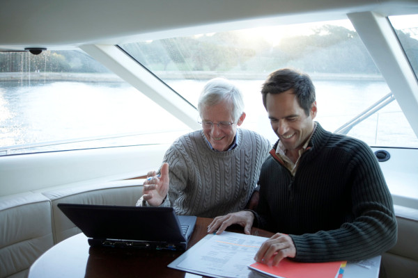 Father and son reviewing paperwork on a yacht